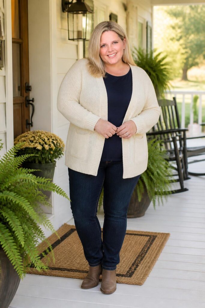 Candace Alley standing on a farmhouse porch in a cream cardigan